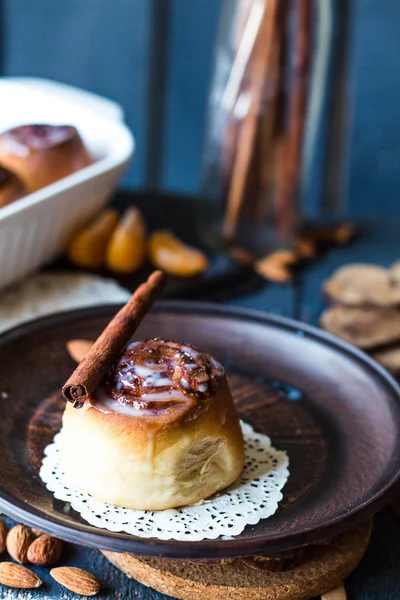Cinnabon cinnamon rolls, almonds and mandarins on a dark plate — Stock Photo, Image