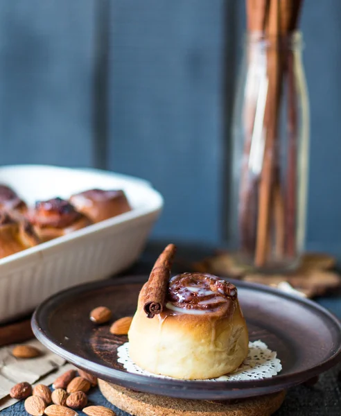 Cinnabon cinnamon rolls, almonds and mandarins on a dark plate — Stock Photo, Image