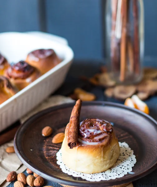 Cinnabon cinnamon rolls, almonds and mandarins on a dark plate — Stock Photo, Image