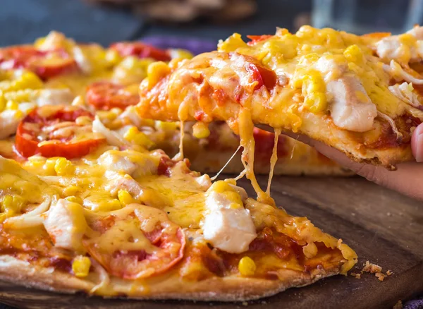 Eating pizza with chicken, corn, tomatoes and cheese double, han — Stock Photo, Image