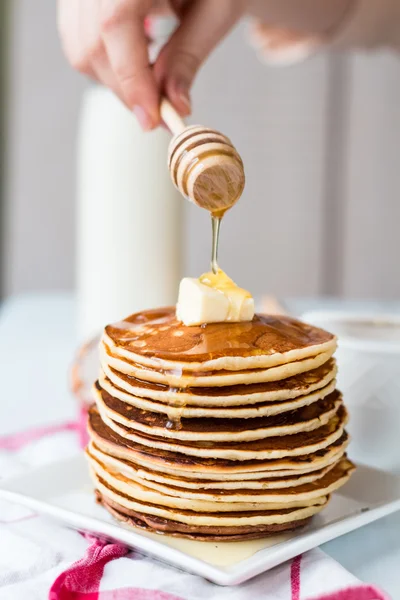 Haufen Pfannkuchen mit Butter, Honigsauce hinzufügen, Hände — Stockfoto