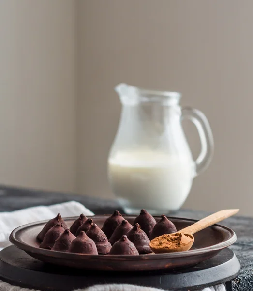 Candy chocolate truffles on a plate of dark and cream in a jug, — Stock Photo, Image