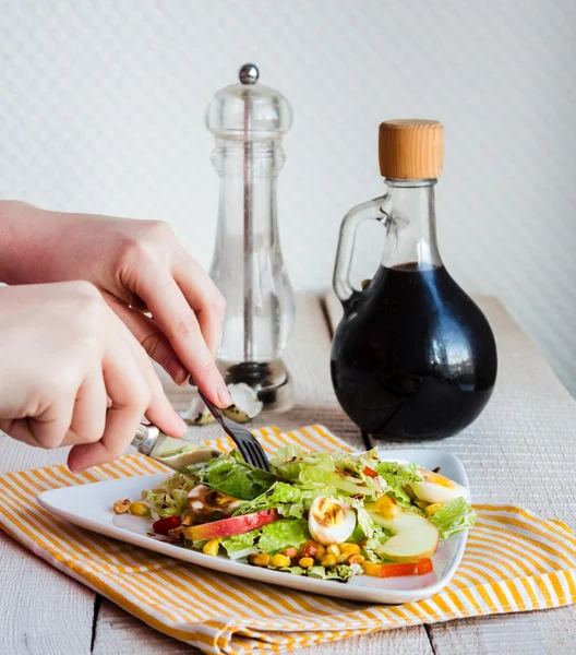 Mangiare insalata verde con uova di quaglia, mais e mela, mani — Foto Stock