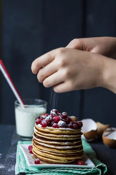 American pancake with berries sprinkled with powdered, hands