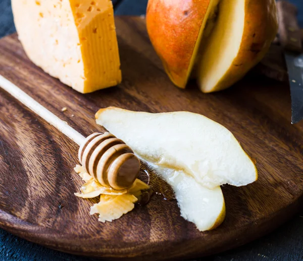 Poire fraîche juteuse au fromage et miel sur une planche de bois — Photo