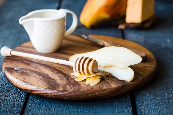 Pêra suculenta fresca com queijo e mel em uma tábua de madeira — Fotografia de Stock