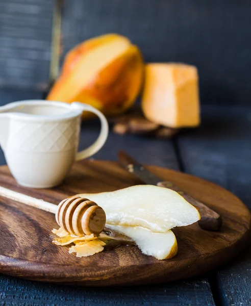 Peral fresca y jugosa con queso y miel en una tabla de madera —  Fotos de Stock