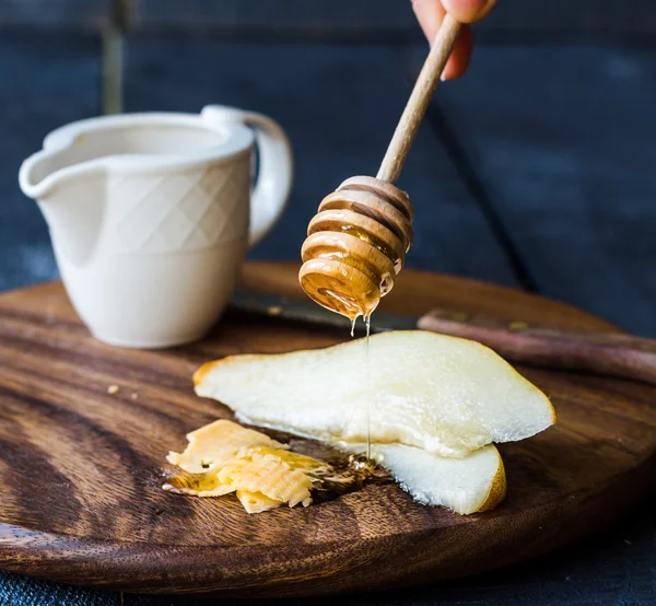 Peral fresca y jugosa con queso y miel en una tabla de madera —  Fotos de Stock