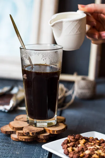 Sahne zu schwarzer Kaffeetasse hinzufügen, Hand — Stockfoto