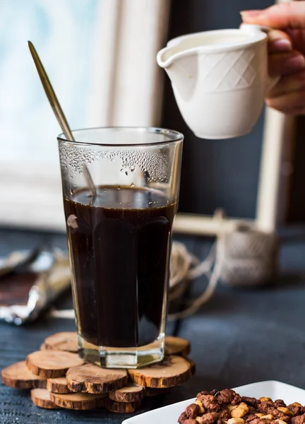 Sahne zu schwarzer Kaffeetasse hinzufügen, Hand — Stockfoto