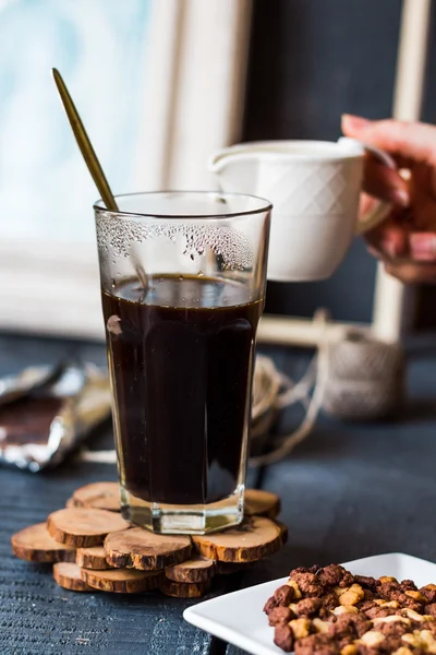 Sahne zu schwarzer Kaffeetasse hinzufügen, Hand — Stockfoto