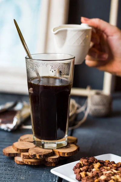 Додати вершки до чорної чашки кави, рука — стокове фото