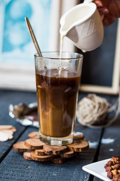 Tillsätt grädde till svart kaffe cup, hand — Stockfoto