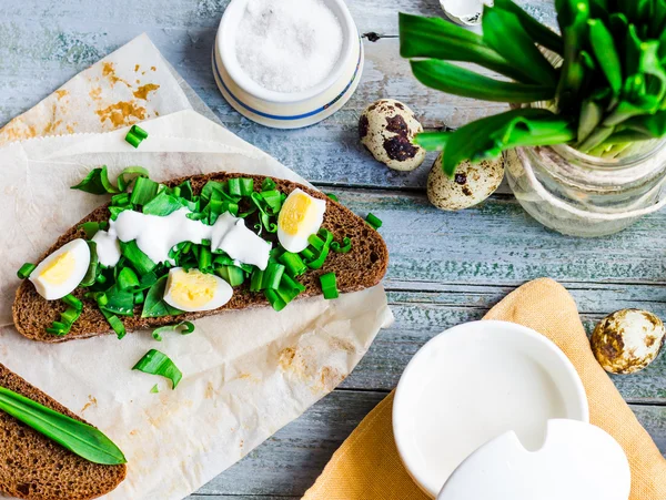 Pane di segale con aglio selvatico, panna acida e uova di quaglia, spuntino, a — Foto Stock