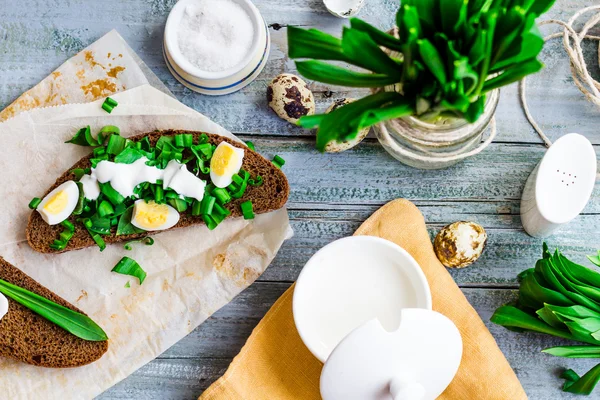 Pan de centeno con ajo silvestre, crema agria y huevos de codorniz —  Fotos de Stock