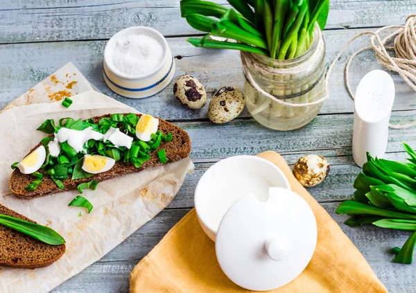 Rye bread with wild garlic, sour cream and quail eggs,top view — Stock Photo, Image