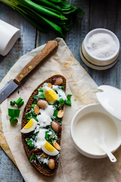 Rye bread with wild garlic, sour cream and quail eggs and beans — Stock Photo, Image
