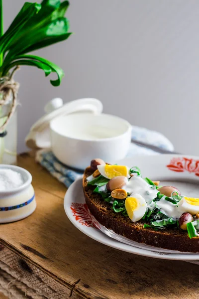 Leek with quail eggs and sour cream on rye bread, snack — Stock Photo, Image
