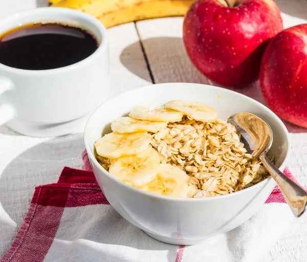 Havregrynsgröt med bananer, äpplen och en kopp kaffe — Stockfoto