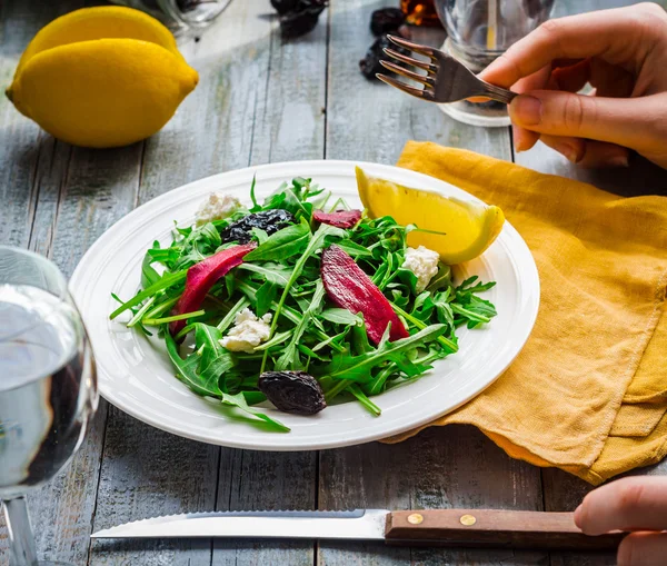 Їдять зелений салат з руколою, буряком, козячим сиром та оливковою олією — стокове фото
