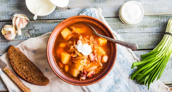 Röd borsch med bönor, gräddfil, ramslök, rågbröd, rusti — Stockfoto