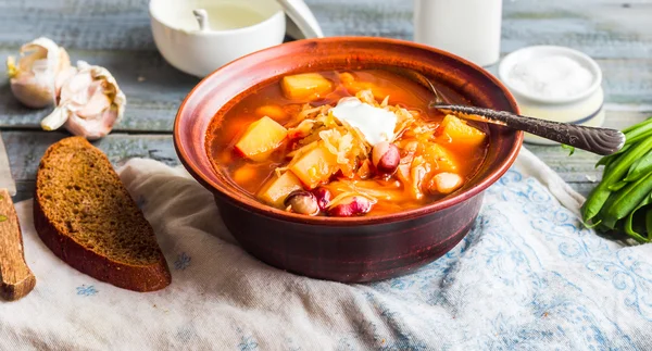 Röd borsch med bönor, gräddfil, ramslök, rågbröd, rusti — Stockfoto