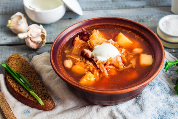 Röd borsch med bönor, gräddfil, ramslök, rågbröd, rusti — Stockfoto