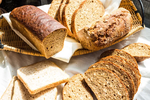 Fatias de pão sortidas em um cesto em uma toalha de mesa de linho branco — Fotografia de Stock