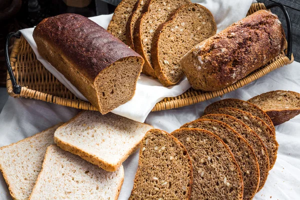 Sortierte Brotscheiben in einem Korb auf einem weißen Leinentischtuch — Stockfoto