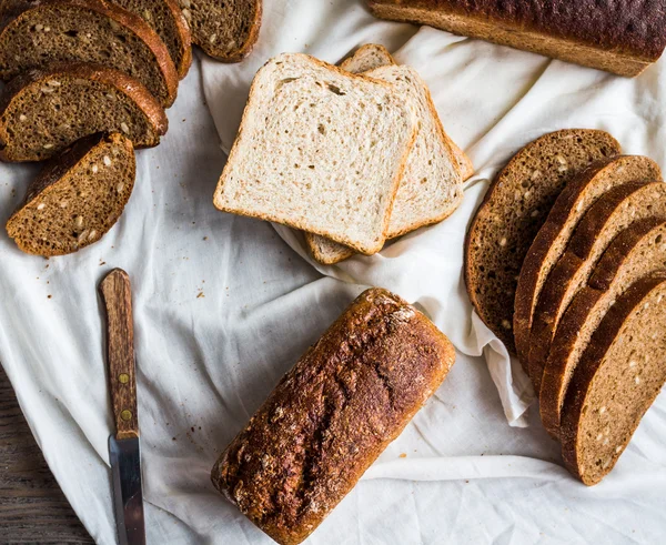 Разнообразный хлеб, ломтики ржаного хлеба на льняных скатертях, деревянные — стоковое фото