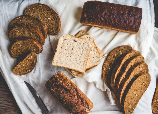 Pane assortito, fette di pane di segale su tovaglie di lino, legno — Foto Stock