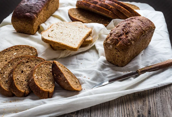 Assorted bread, slices of rye bread on linen tablecloths, wooden — Stock Photo, Image