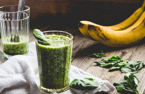 Grøn smoothie med spinatblade, banan med jordnøddemælk i en - Stock-foto