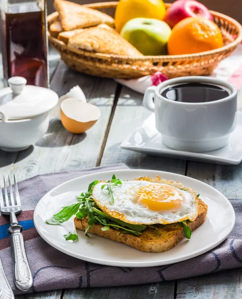 Pain grillé croustillant avec un oeuf frit et roquette verte, tasse de café, fru — Photo