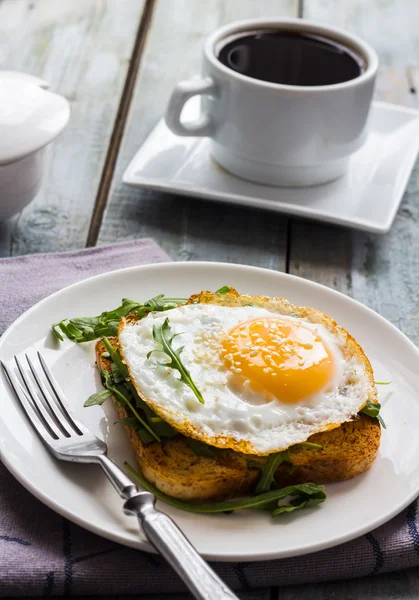 Pain grillé croustillant avec un oeuf frit et roquette fraîche, une tasse de café — Photo