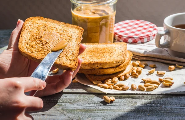 Ajouter au pain grillé roux beurre d'arachide, main, délicieux petit déjeuner — Photo