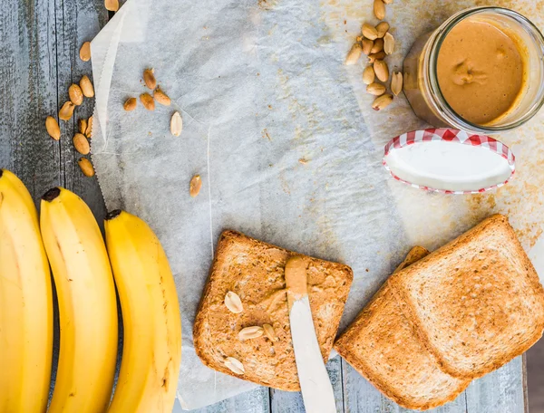 ขนมปังกรอบกับเนยถั่ว, กล้วย, อาหารเช้า — ภาพถ่ายสต็อก