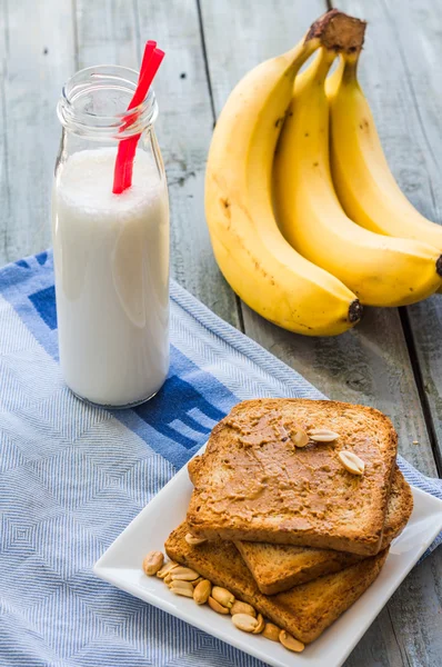 Banana smoothie, toast with peanut butter, roasted peanuts, brea — Stock Photo, Image