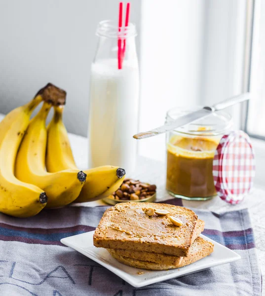 Banaanismoothie, paahtoleipää maapähkinävoilla, paahdettuja maapähkinöitä, brea — kuvapankkivalokuva