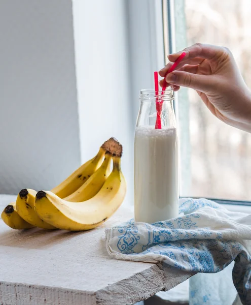 Banana smoothie in a glass bottle, fresh bananas, drink, hand — Stock Photo, Image