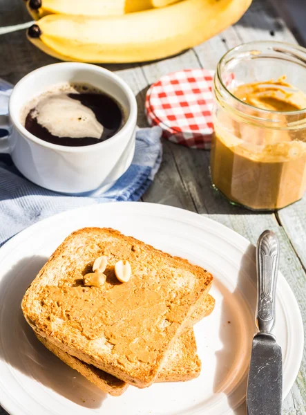 Ruddy toast with peanut butter, fresh bananas, coffee, breakfast — Stock Photo, Image