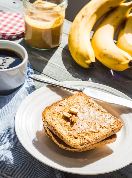 Ruddy toast with peanut butter, fresh bananas, coffee, breakfast — Stock Photo, Image