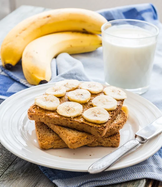 Ruddy toast with peanut butter, sliced bananas, milk, breakfast — Stock Photo, Image