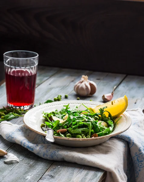 Green salad with arugula, cheese, almonds, lemon, garlic — Stock Photo, Image