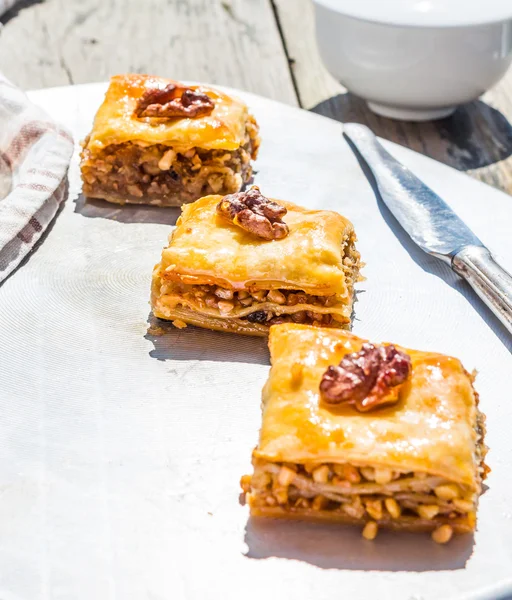 Pedaços de baklava doce no prato, jardim verde fundo — Fotografia de Stock