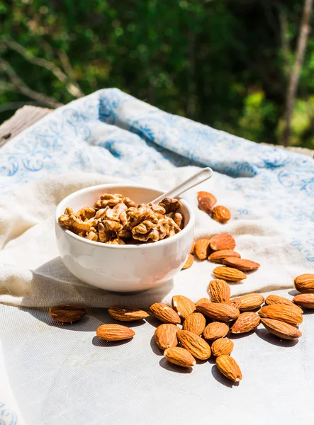 Nuts, almonds and walnuts in a white plate on a light background — Stock Photo, Image