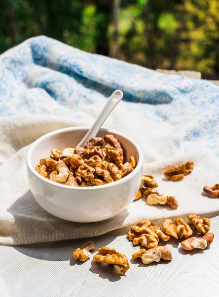 Nuts, almonds and walnuts in a white plate on a light background — Stock Photo, Image