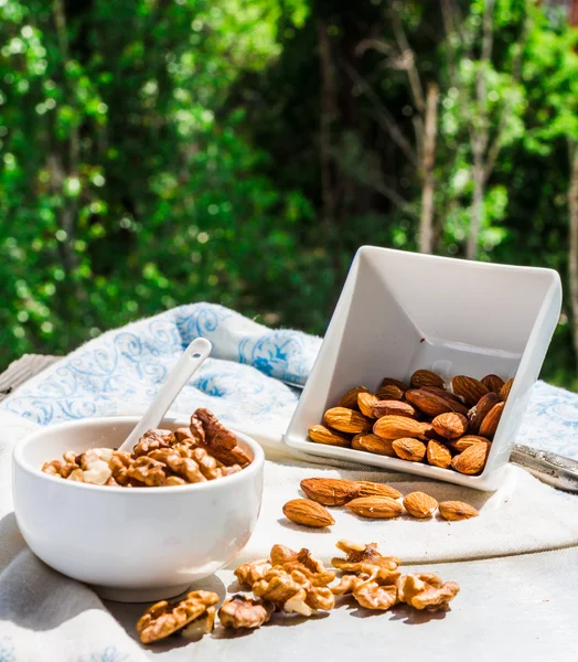 Nuts, almonds and walnuts in a white plate on a light background — Stock Photo, Image