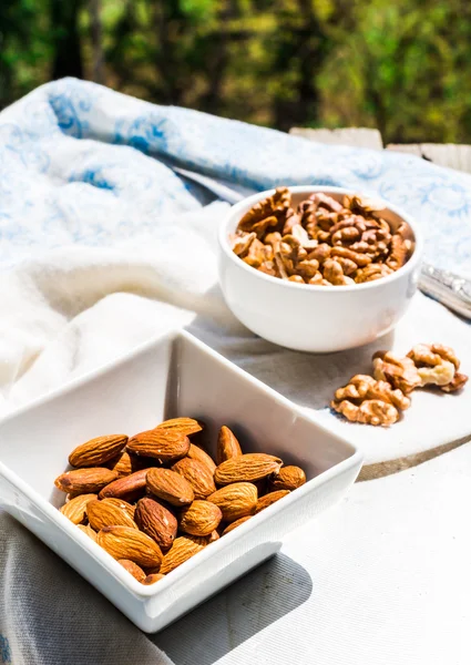 Nuts, almonds and walnuts in a white plate on a light background — Stock Photo, Image