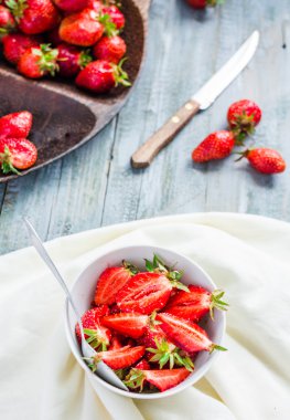 Beyaz tabak, mavi arka plan, s sulu kırmızı çilek dilimleri